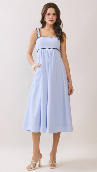 Woman wearing a light blue dress with black trim on a white background
