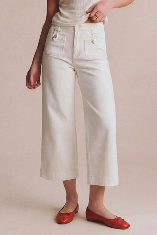 Person wearing white wide-leg pants and red shoes on a beige background