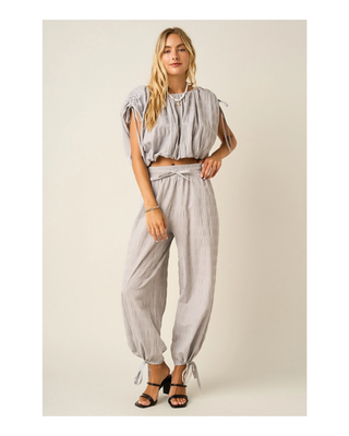 The Maren Bubble Top in light gray featuring textured fabric, adjustable shoulder ties, an elastic neckline, and a flattering bubble hem.