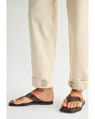 Women's cream high-rise wide leg jeans with cropped ankle length and double-button cuff detail, styled with a black cardigan and sandals.
