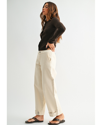 Women's cream high-rise wide leg jeans with cropped ankle length and double-button cuff detail, styled with a black cardigan and sandals.