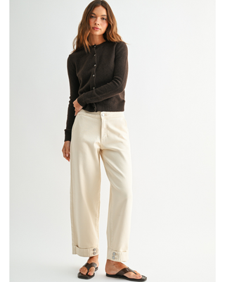 Women's cream high-rise wide leg jeans with cropped ankle length and double-button cuff detail, styled with a black cardigan and sandals.