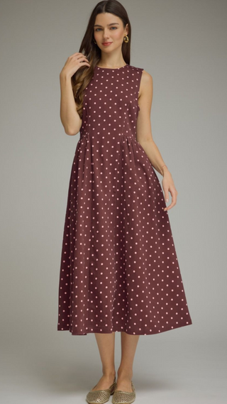 Round neckline sleeveless crimson dress with pink polka dots a gathered waist forming waist with an A-line pleated midi skirt