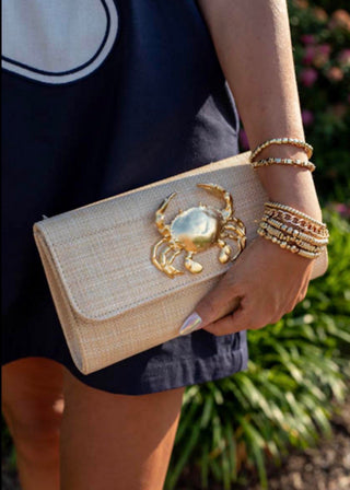Natural woven envelope clutch purse featuring a gold crab embellishment, perfect for coastal fashion, beach weddings, vacations, resort wear, and special occasions.