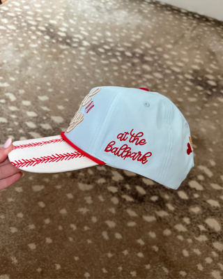 Side view of the baseball trucker hat showing its light blue mesh back and red contrast stitching.