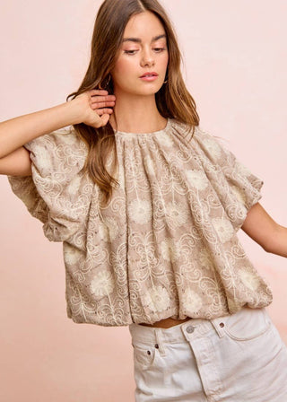 Woman wearing a beige lace bubble blouse with puff short sleeves