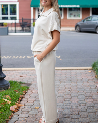 Model wearing neutral beige wide-leg lounge pants with an adjustable drawstring waistband and front seam detailing.