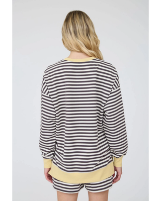 A woman modeling a matching lounge set consisting of a long-sleeve top and shorts in a gray and white horizontal stripe pattern with yellow ribbed trim.