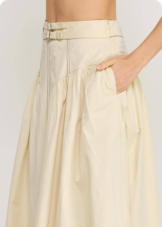 Close up of woman wearing a skirt from a matching set, in a cream color with top stitch and buckle accent on waist.