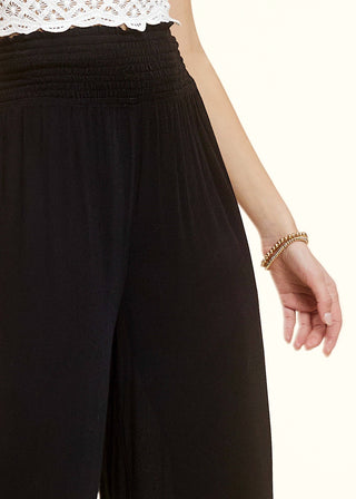 Close up on waist part of smocked high waisted wide legged lightweight flowy pants in black