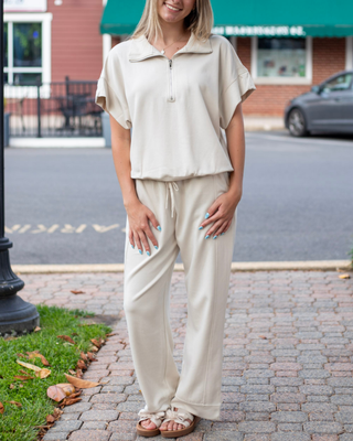 Model wearing neutral beige wide-leg lounge pants with an adjustable drawstring waistband and front seam detailing.