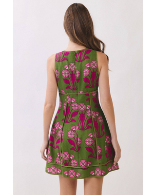 Woman wearing an olive green sleeveless fit-and-flare mini dress with vibrant fuchsia floral jacquard detailing, styled for weddings, brunches, and garden parties.