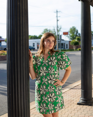 Model wearing a green floral shift dress with oversized ivory flower print, puff sleeves, and a split V-neckline.