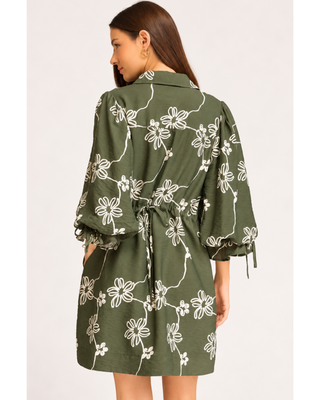 Olive green floral mini dress with cream abstract flower print, collared V-neckline, balloon sleeves with tie cuffs, and side pockets.