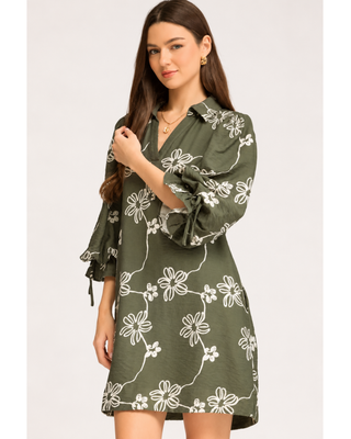 Olive green floral mini dress with cream abstract flower print, collared V-neckline, balloon sleeves with tie cuffs, and side pockets.