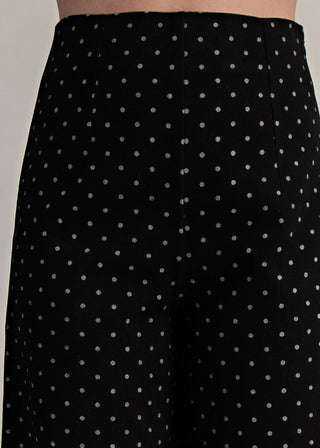 Black pants with white polka dots worn by a person.