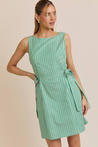 Woman wearing a green and white striped dress against a beige background
