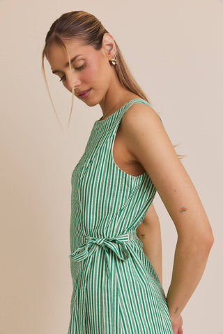 Woman wearing a green and white striped dress against a beige background