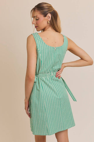 Woman wearing a green and white striped dress against a beige background