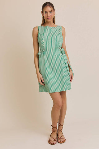 Woman wearing a green and white striped dress on a beige background
