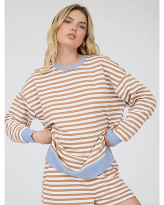 A woman modeling a matching lounge set consisting of a long-sleeve top and shorts in a beige and white horizontal stripe pattern with light blue ribbed trim.