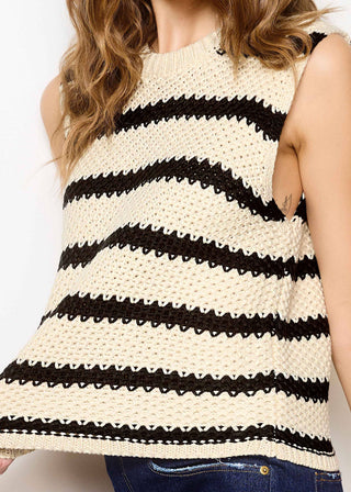Woman wearing a sleeveless black and white striped top on a plain background