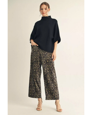 Woman wearing leopard print high-rise wide-leg cropped pants with a black top and neutral heels.