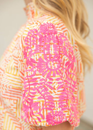 Person wearing a colorful patterned shirt with pink and orange design.