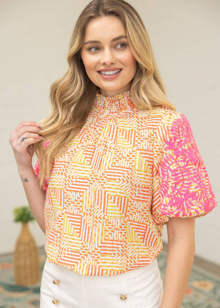 Woman wearing a colorful patterned top with a neutral background