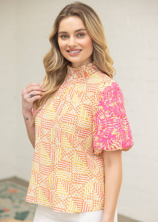 Woman wearing a colorful patterned top with a blurred background