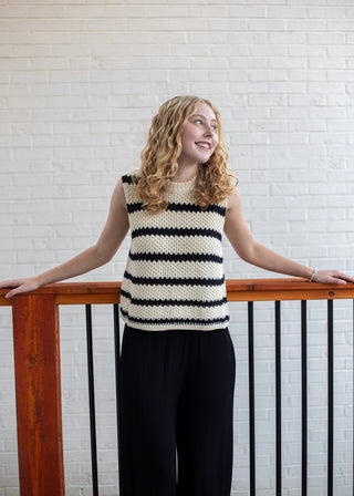 A woman wearing a sleeveless knit top with horizontal black and cream stripes 