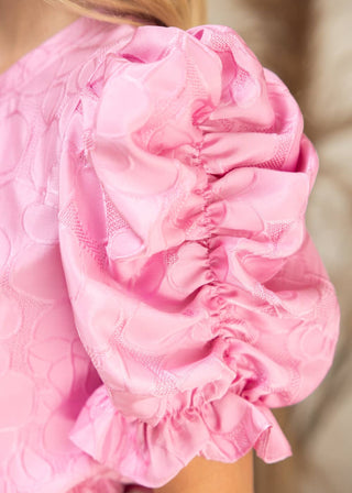 Close-up of a pink textured garment with ruffled details.