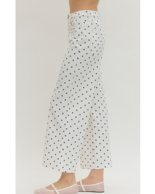 Women's ivory wide leg pants with a classic black polka dot print, styled with a black bow blouse in a boutique for a chic and sophisticated outfit.