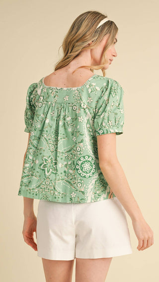 Woman wearing a green floral blouse showing the back of the square neck top 