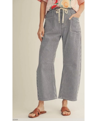 Woman wearing blue and white pinstripe wide-leg pants with a high-rise drawstring waistband and utility pockets, styled with a casual graphic tee and sandals for an effortless everyday look.