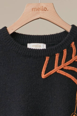 Black Halloween knit sweater with orange embroidered spiderweb designs and hanging spider detail, styled with distressed denim shorts.