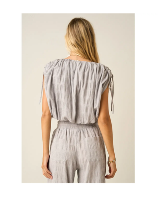 The Maren Bubble Top in light gray featuring textured fabric, adjustable shoulder ties, an elastic neckline, and a flattering bubble hem.