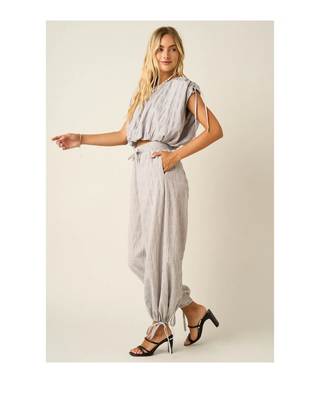 The Maren Jogger Pants in light gray featuring textured fabric, an elastic drawstring waistband, relaxed fit, and adjustable ankle ties.