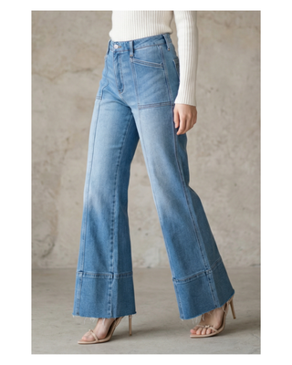 The Sutton Palazzo Jeans featuring eco-friendly light wash stretch denim, a high-rise tummy control waistband, front seam detailing, and a wide palazzo leg with a raw hem.