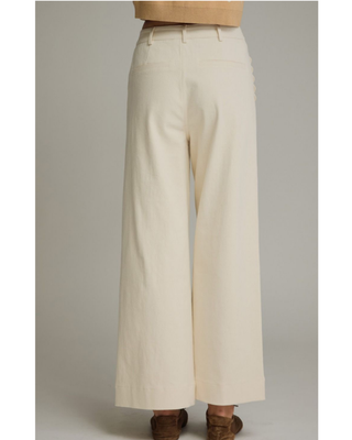 Women's ivory wide-leg pants with a high-rise waist and decorative scalloped front pockets, styled for a chic boutique outfit.