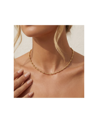 Delicate gold beaded necklace with alternating bead sizes worn as a short necklace for women.