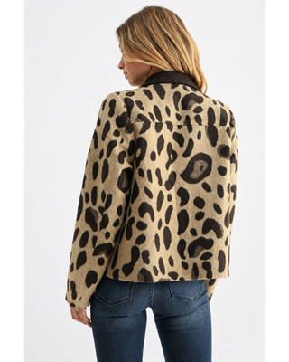 Woman wearing a taupe and dark brown leopard print zip-front jacket with a contrasting brown collar and pocket trim, styled with a white top and dark denim jeans.