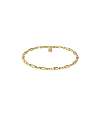 Delicate gold beaded bracelet with polished oval bead accents worn on a woman’s wrist.