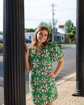 Model wearing a green floral shift dress with oversized ivory flower print, puff sleeves, and a split V-neckline.