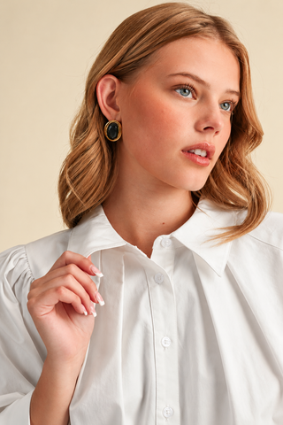 Model wearing a white button-down blouse with puff sleeves, pointed collar, and wide cuffs, paired with a red plaid bubble skirt.