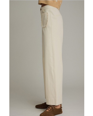 Women's ivory wide-leg pants with a high-rise waist and decorative scalloped front pockets, styled for a chic boutique outfit.