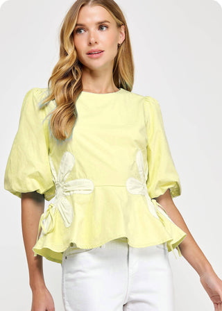 Woman wearing a light yellow blouse with bow details on a white background