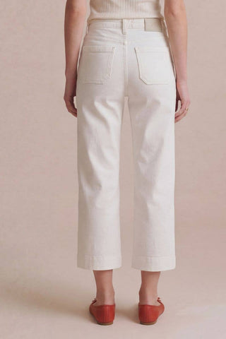 Person wearing white wide-leg pants and red shoes on a beige background