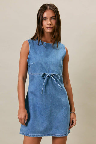 Woman wearing a blue denim dress against a neutral background