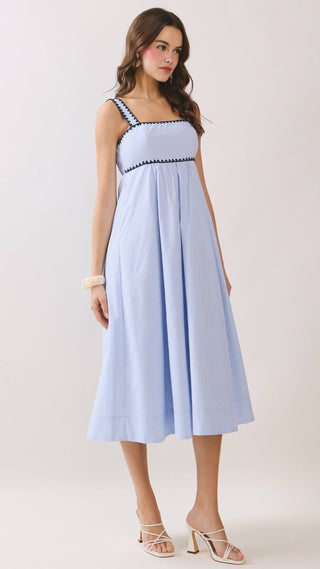 Woman wearing a light blue dress with black trim on a white background